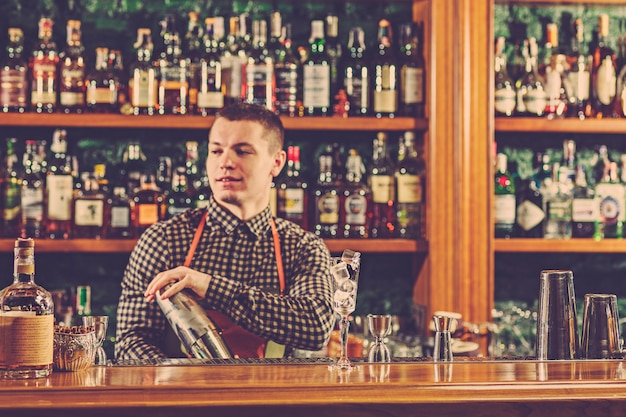 The barman making an alcoholic cocktail at the bar counter on the bar space