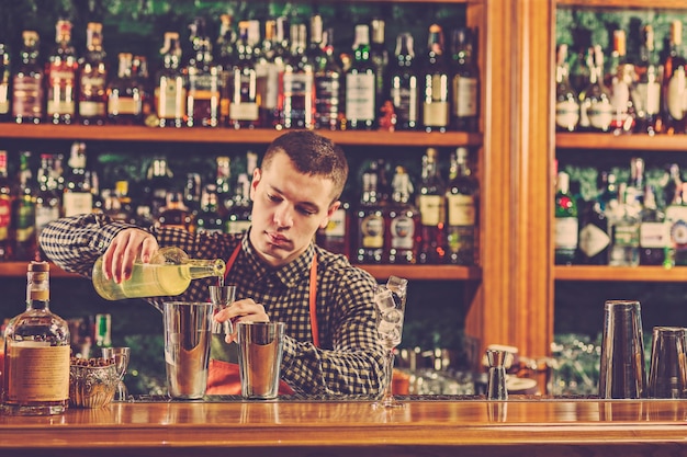 Foto gratuita barman che prepara un cocktail alcolico al bancone del bar