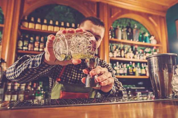 Barman making an alcoholic cocktail at the bar counter on the bar 