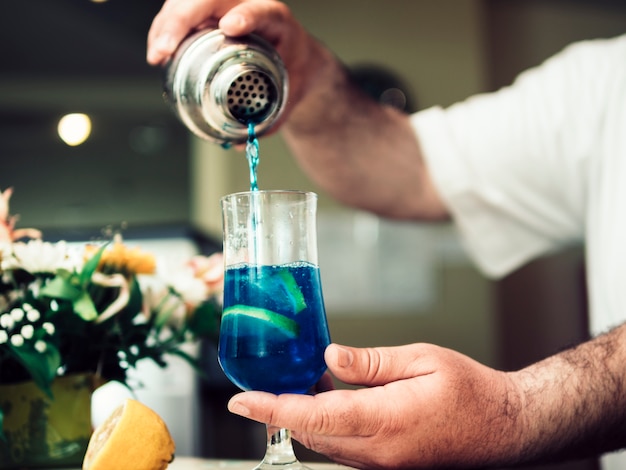 Barman pouring alcoholic drink in cocktail 