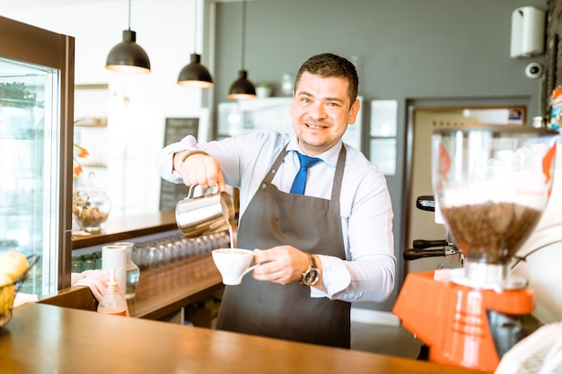 Barman pouring milk in coffee