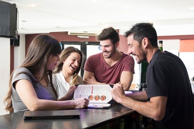 Free photo barman showing menu to customers at the bar counter