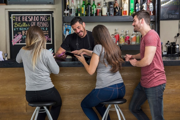 Free photo barman showing menu to customers in the bar