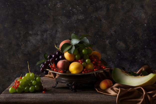 Foto gratuita stile barocco con composizione di frutta e stoffa