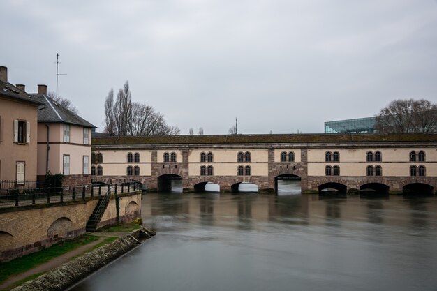 Barrage Vauban surrounded by water and buildings under a cloudy sky in Strasbourg in France
