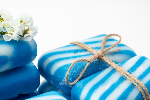 Bars of handmade natural soap and flowers on white background