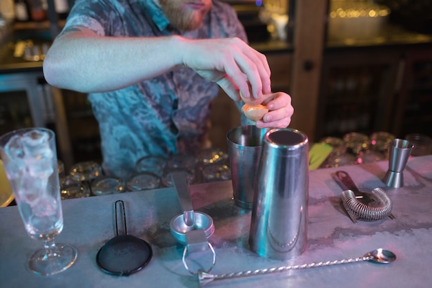 Free photo bartender adding egg yolk while preparing drink at counter