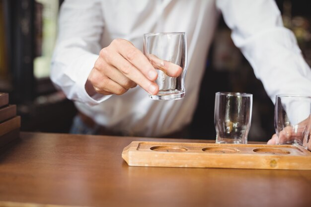 Bartender arranging beer glass on tray at bar counter