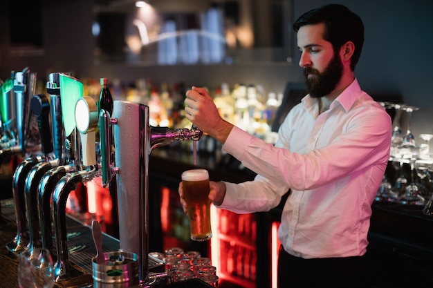 Free photo bartender filling beer from bar pump
