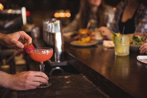 Bartender holding cocktail at bar counter