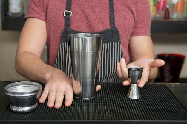 Bartender is adding ingredient in shaker at bar counter