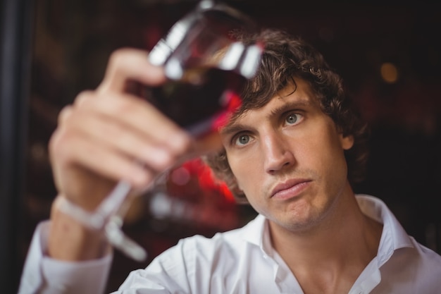 Бармен смотрит на бокал красного вина