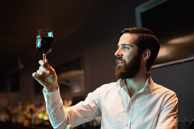 Bartender looking at glass of red wine