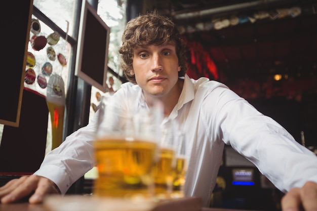 Free photo bartender looking at glasses of beer