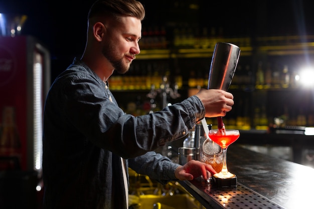 Foto gratuita barista che prepara un cocktail con uno shaker