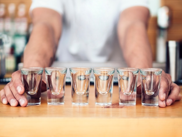 Free photo bartender placing line of shot glasses on counter