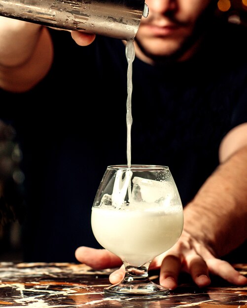 Bartender pours cocktail into a glass