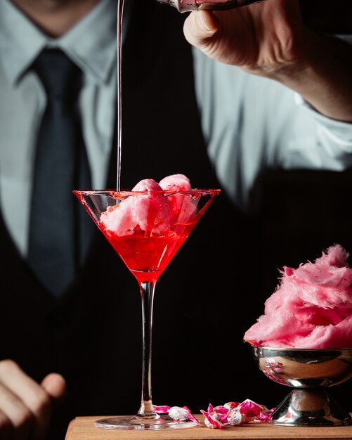 Bartender prepares sweet cotton cocktail in martini glass