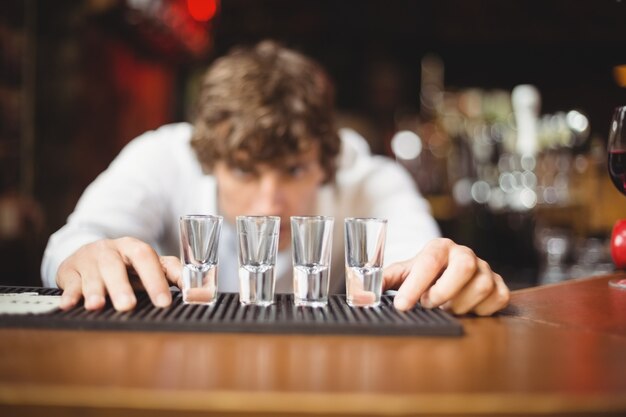 Bartender preparing and lining shot glasses for alcoholic drinks on bar counter