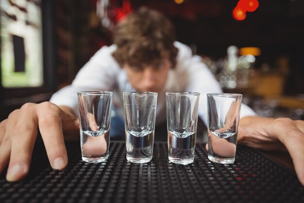 Bartender preparing and lining shot glasses for alcoholic drinks on bar counter