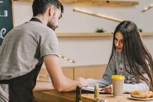 Foto gratuita barista che mostra i prezzi al cliente