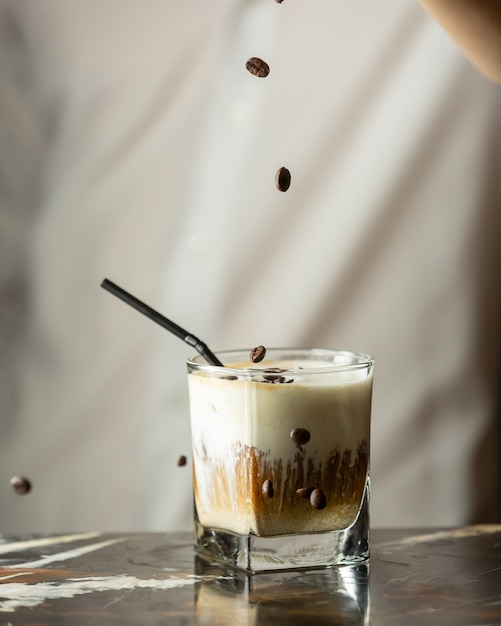 Bartender sprinkles coffee beans into iced coffee drink