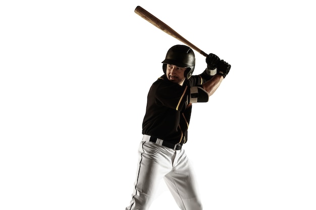 Baseball player, pitcher in a black uniform practicing and training isolated on a white wall. Young professional sportsman in action and motion. Healthy lifestyle, sport, movement concept.