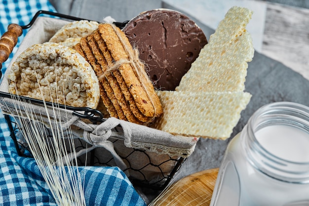 Basket of biscuits and a jar of milk on a marble table, close up.