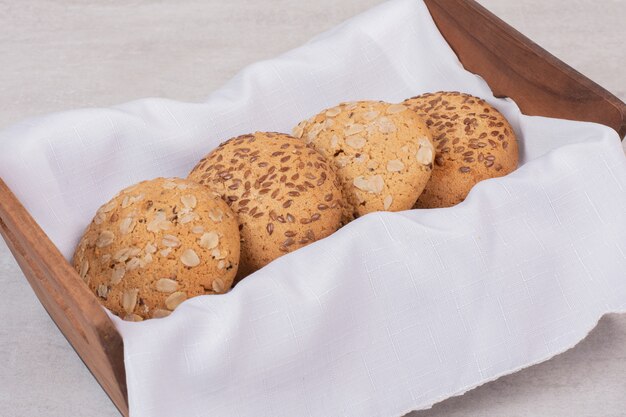 Basket of cookies with sesame seeds on white surface.