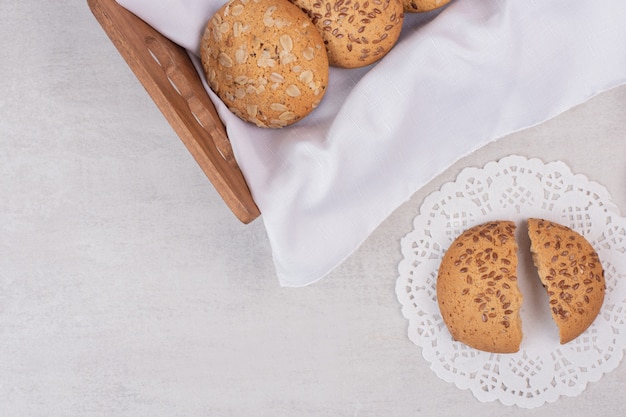 Basket of cookies with sesame seeds on white surface.