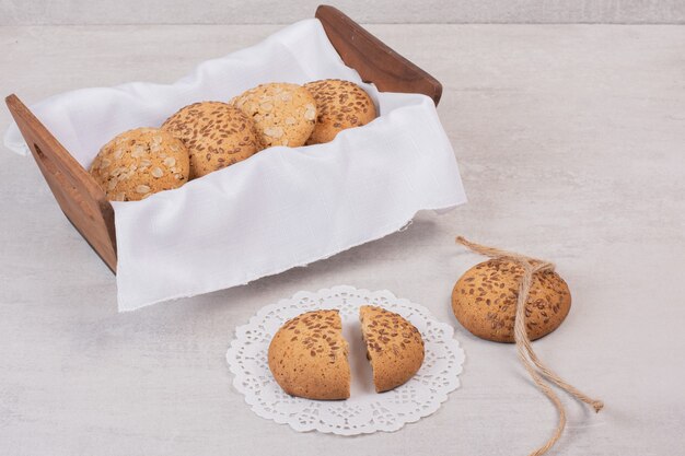 Basket of cookies with sesame seeds on white surface.