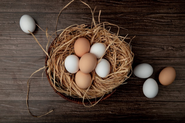 Free photo basket of eggs in nest with eggs around on wooden table