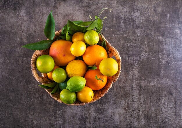 Basket filled with citrus fruits on grey stone surface