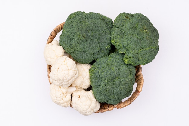 Free photo basket full of broccoli and cauliflower bunches top view on white surface