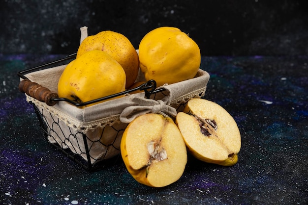 Basket full of fresh ripe quinces on dark table. 