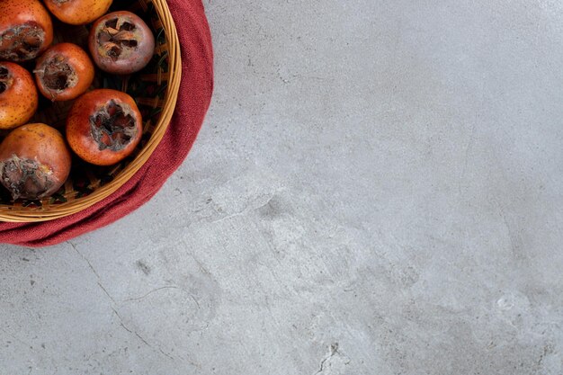 Basket of kakis with seeds removed on marble table.