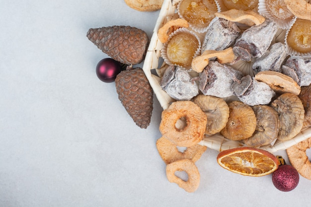 A basket of mixed healthy dried fruits with pinecones . High quality photo