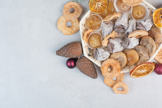 A basket of mixed healthy dried fruits with pinecones . High quality photo