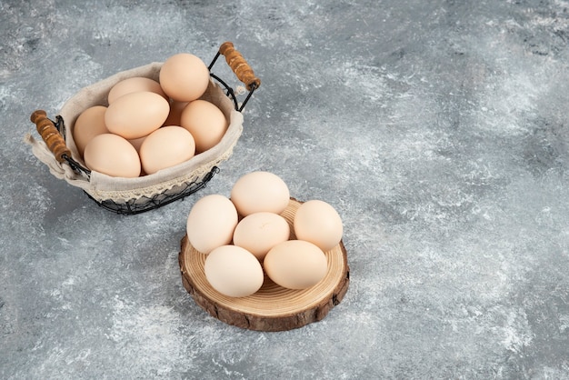 Basket of organic fresh uncooked eggs placed on marble surface.