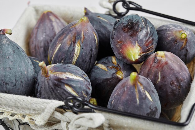 A basket of purple figs on white.