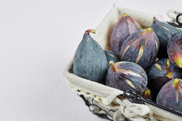 A basket of purple figs on white.