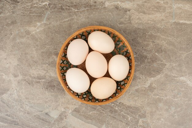 Basket of white eggs on marble table .