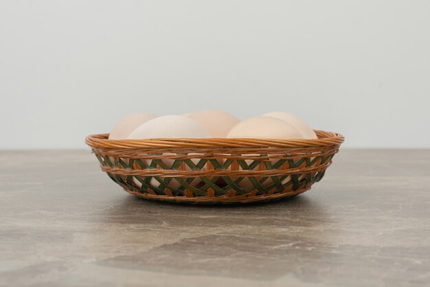 Basket of white eggs on marble table .