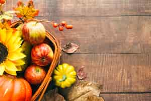 Free photo basket with autumnal harvest and sunflower on table