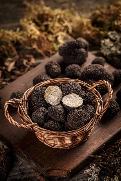 Basket with black truffles on dark wooden board