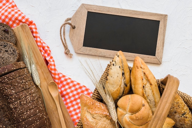 Basket with buns near bread and blackboard