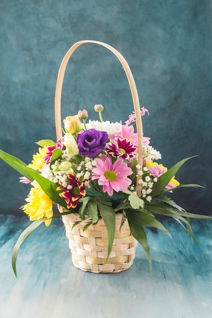 Basket with different flowers placed on desk