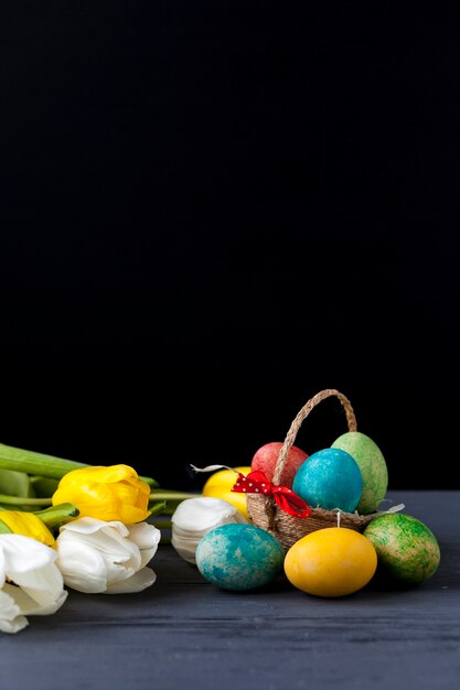 Basket with eggs and tulips on black