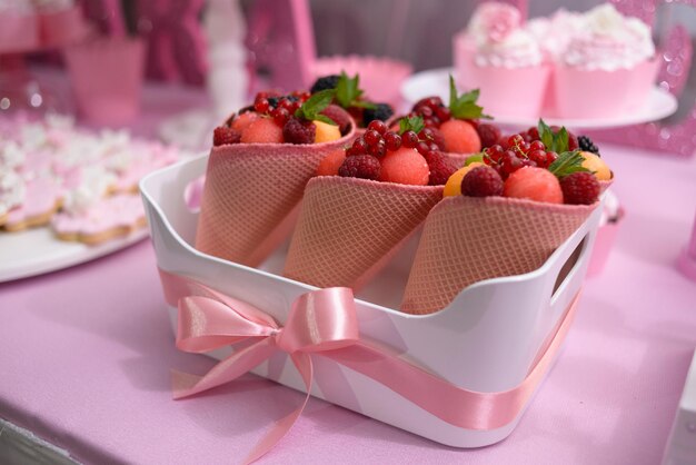 Basket with fresh fruit and berries in waffle cones on a festive table