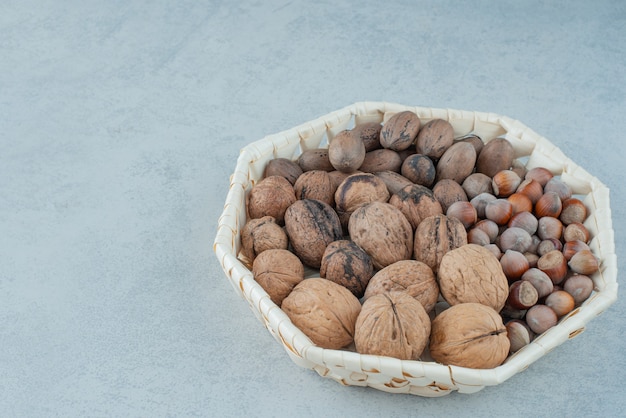 大理石の背景に健康的なナッツのバスケット。高品質の写真